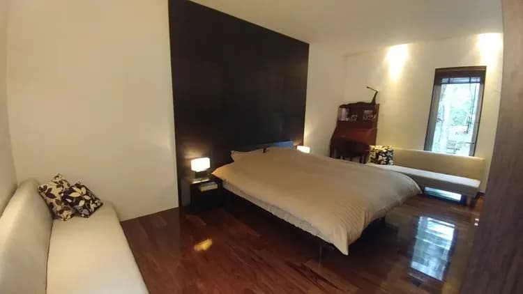 リビングスペースとパーテーションで区切ったベッドスペース｡クイーンサイズのベッドの両側にソファーベッドを設置