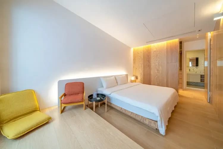 3樓木紋控房型｜大地色木紋與柔光牆面交織溫潤氛圍，床邊角落適合展開慵懶的午後時光。