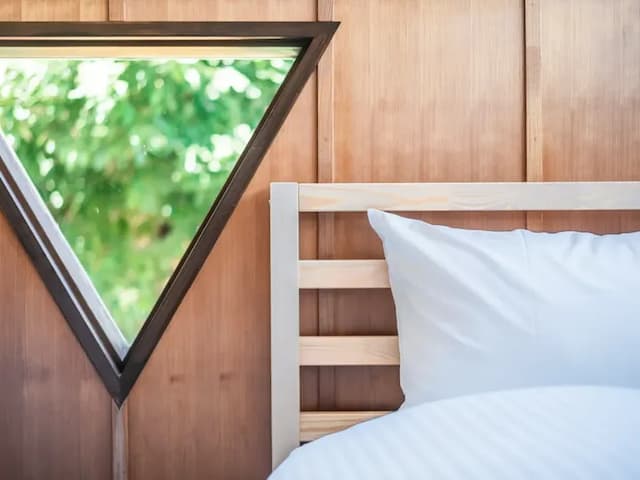・【ベッドルーム】サンカク窓から覗く緑とログハウス風の内装がマッチ