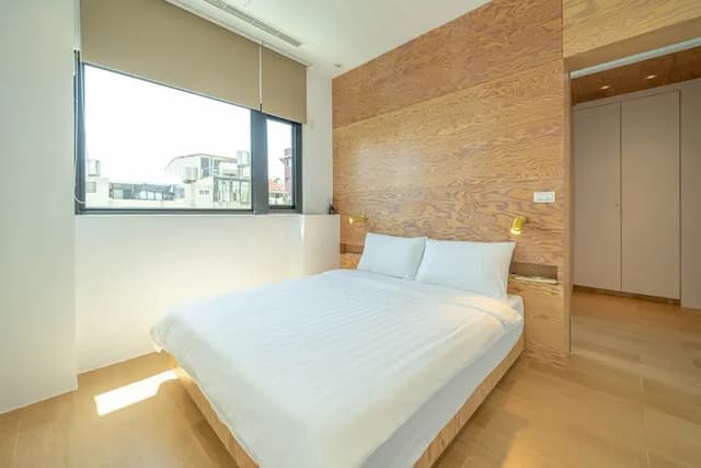 臥室設有大面窗與木紋牆面，搭配加大床墊，溫潤靜謐。