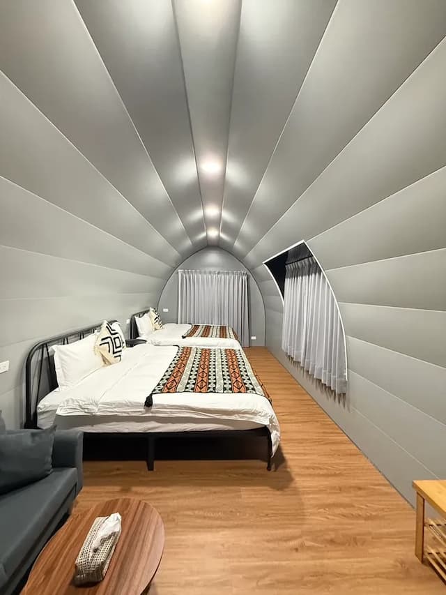 灰階金屬調牆面結合木地板，營造極簡現代感，搭配雙人大床，適合雙人或家庭入住。