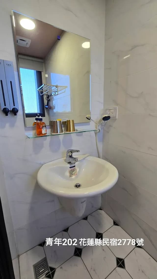 乾淨明亮的浴室，配備洗手台、鏡子與基本盥洗用品。